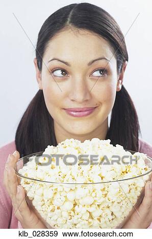 Stock Photo - Young woman holding bowl of popcorn. Fotosearch