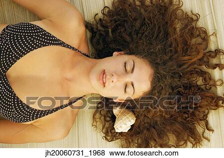 Young woman laying next to seashell View Large Photo Image Stock Photo - Young woman laying next to seashell. Fotosearch