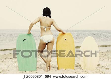 Young woman leaning on boogie boards at beach View Large Photo Image Picture - Young woman leaning on boogie boards at beach. Fotosearch
