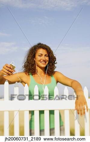 Stock Photo - Young woman listening to mp3 player. Fotosearch