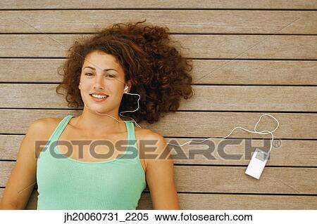 Stock Photography - Young woman listening to mp3 player. Fotosearch