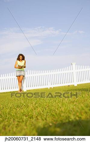 Young woman reading outdoors View Large Photo Image Stock Photo - Young woman reading outdoors. Fotosearch