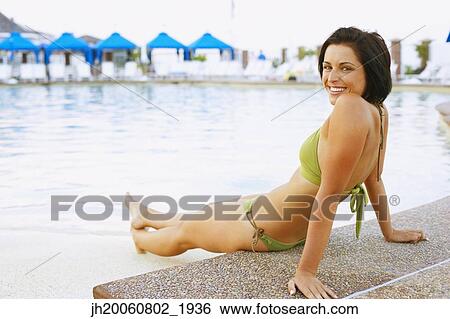 Young woman sitting next to swimming pool View Large Photo Image Stock Photograph - Young woman sitting next to swimming pool. Fotosearch