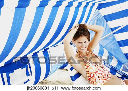 Young woman sitting under beach sun shade View Large Photo Image Stock Image - Young woman sitting under beach sun shade. Fotosearch