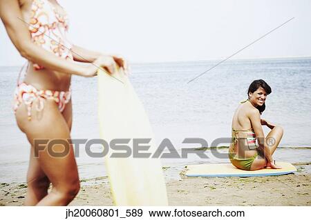 Stock Photo - Young women with boogie boards at beach. Fotosearch