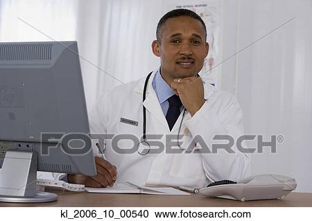 Stock Image - African doctor writing in notebook. Fotosearch