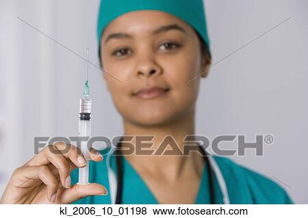 Stock Photo - African female doctor holding syringe. Fotosearch