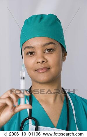 Stock Photograph - African female doctor holding syringe. Fotosearch