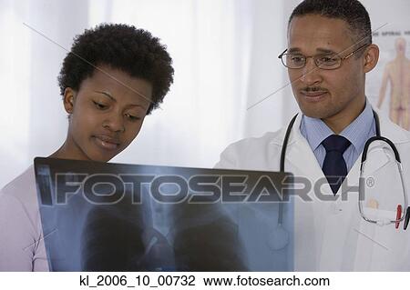 Stock Image - African male doctor and patient looking at x-ray. Fotosearch