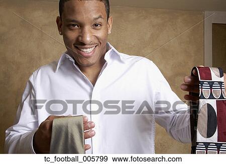 Stock Photo - African man holding up two ties. Fotosearch