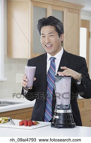 Stock Image - Asian businessman drinking fruit smoothie. Fotosearch