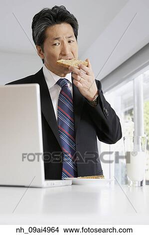 Asian businessman eating toast View Large Photo Image Picture - Asian businessman eating toast. Fotosearch