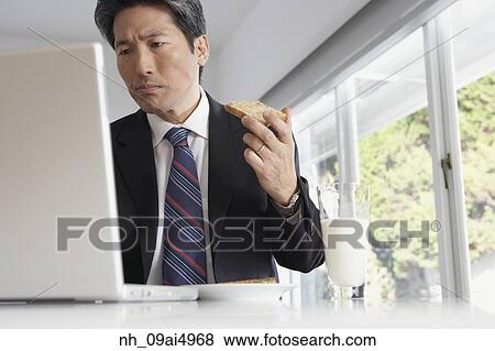 Asian businessman eating toast View Large Photo Image Stock Photo - Asian businessman eating toast. Fotosearch