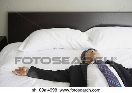 Asian businessman laying on bed View Large Photo Image Stock Photo - Asian businessman laying on bed. Fotosearch