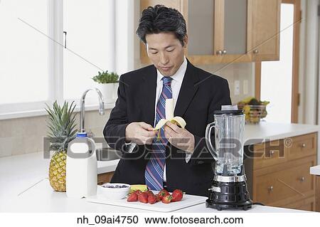 Stock Image - Asian businessman making fruit smoothie. Fotosearch