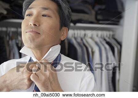 Asian businessman putting on tie View Large Photo Image Stock Image - Asian businessman putting on tie. Fotosearch