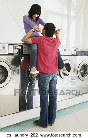 Stock Image - Asian couple in laundromat. Fotosearch