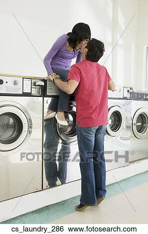 Stock Photograph - Asian couple kissing in laundromat. Fotosearch