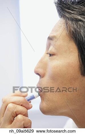 Asian man applying lip balm View Large Photo Image Stock Photo - Asian man applying lip balm. Fotosearch