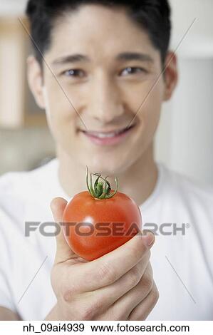 Asian man holding tomato View Large Photo Image Stock Photo - Asian man holding tomato. Fotosearch