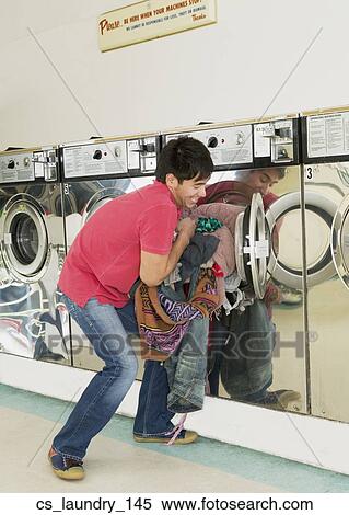 Stock Photography - Asian man in laundromat. Fotosearch