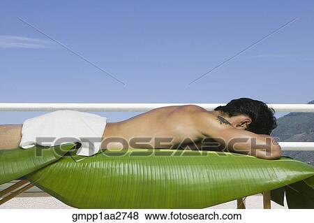 Asian man laying on spa table with banana leaves outdoors View Large Photo Image Stock Photo - Asian man laying on spa table with banana leaves outdoors. Fotosearch
