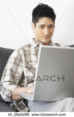 Asian man looking at laptop View Large Photo Image Stock Photograph - Asian man looking at laptop. Fotosearch