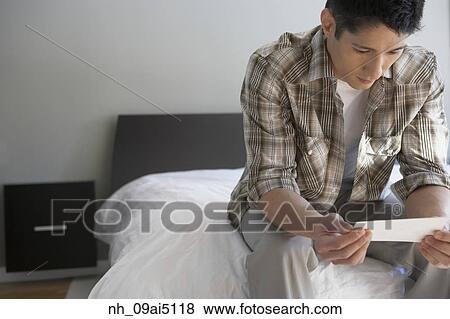Asian man looking at photograph View Large Photo Image Stock Photo - Asian man looking at photograph. Fotosearch
