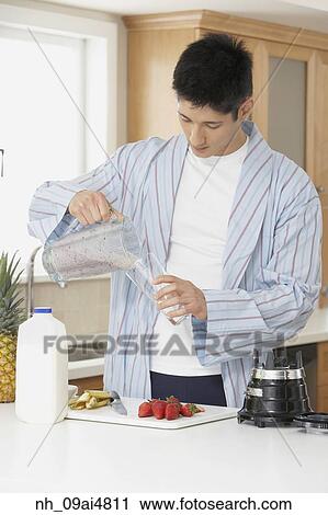 Stock Image - Asian man making fruit smoothie. Fotosearch