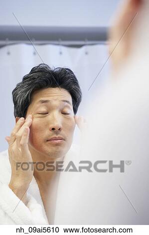 Asian man rubbing face in mirror View Large Photo Image Stock Image - Asian man rubbing face in mirror. Fotosearch