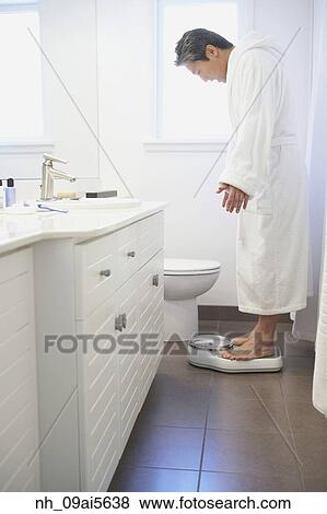 Asian man standing on bathroom scale View Large Photo Image Stock Photo - Asian man standing on bathroom scale. Fotosearch