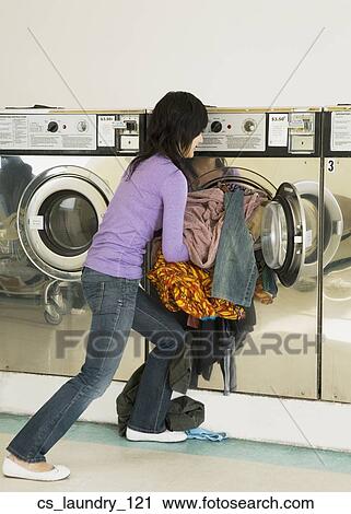 Stock Image - Asian woman in laundromat. Fotosearch