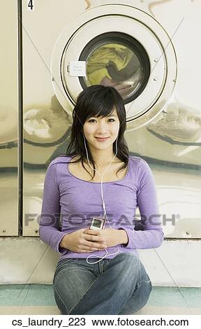 Asian woman listening to mp3 player in laundromat View Large Photo Image Stock Image - Asian woman listening to mp3 player in laundromat. Fotosearch