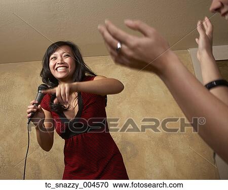 Stock Image - Asian woman singing with microphone. Fotosearch