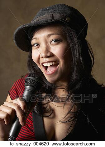 Stock Image - Asian woman singing with microphone. Fotosearch