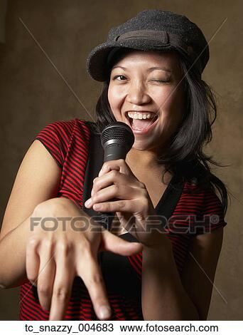 Stock Image - Asian woman singing with microphone. Fotosearch