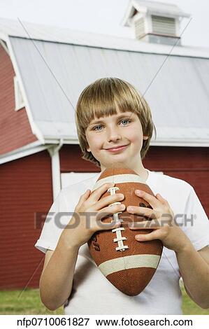 Boy holding football at farm View Large Photo Image Stock Photo - Boy holding football at farm. Fotosearch