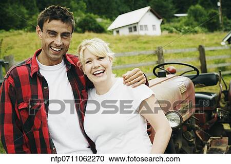Couple standing in front of tractor View Large Photo Image Stock Image - Couple standing in front of tractor. Fotosearch
