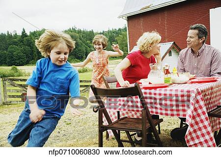 Family eating outdoors on farm View Large Photo Image Stock Image - Family eating outdoors on farm. Fotosearch