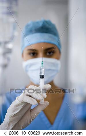Stock Photo - Female doctor holding syringe. Fotosearch