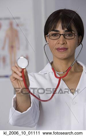 Stock Image - Female doctor holding up stethoscope. Fotosearch
