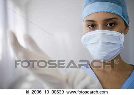 Stock Photo - Female doctor putting on surgical gloves. Fotosearch