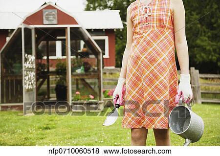 Girl holding gardening supplies on farm View Large Photo Image Stock Photo - Girl holding gardening supplies on farm. Fotosearch