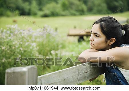Picture - Girl leaning on wooden fence. Fotosearch