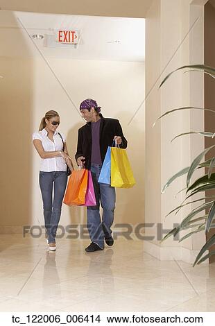Hispanic couple carrying shopping bags View Large Photo Image Picture - Hispanic couple carrying shopping bags. Fotosearch