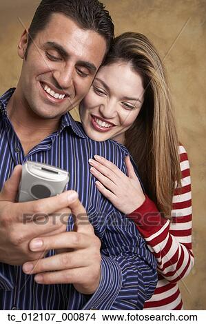 Hispanic couple looking at cell phone View Large Photo Image Picture - Hispanic couple looking at cell phone. Fotosearch