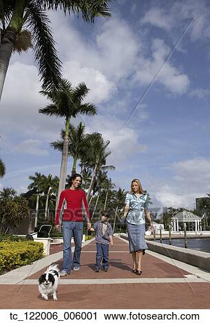 Stock Image - Hispanic family walking dog. Fotosearch