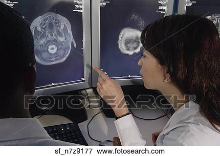 Stock Photo - Hispanic female doctor pointing at brain scans. Fotosearch