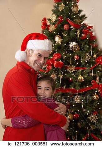 Hispanic girl hugging father in front of Christmas tree View Large Photo Image Stock Image - Hispanic girl hugging father in front of Christmas tree. Fotosearch