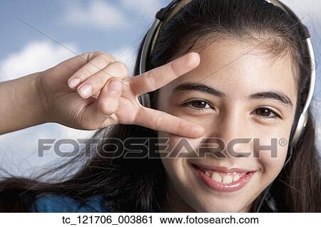 Stock Image - Hispanic girl making peace sign with hand. Fotosearch